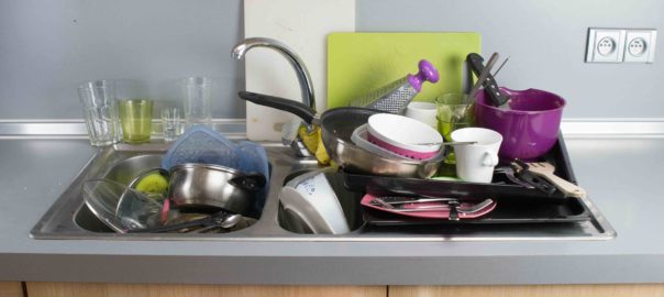 Many dirty dishes in the kitchen sink, in the middle.